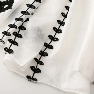Close-up of ethnic style floral embroidery on lightweight white cotton scarf fabric