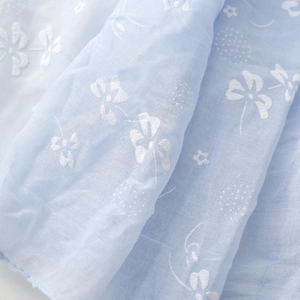Close-up of light blue cotton linen scarf with delicate white floral embroidery patterns