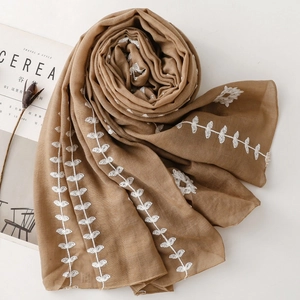 Detail of coffee brown scarf with white floral embroidery and fine rolled edges