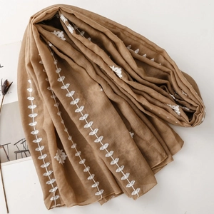 Detailed embroidery of white leaf patterns on a lightweight coffee brown scarf