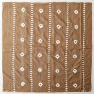 Close-up of brown ethnic shawl with white embroidery patterns and fabric texture