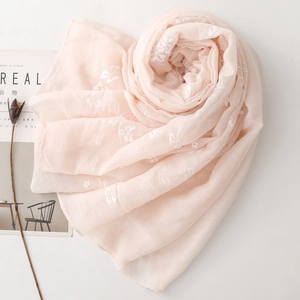 Detailed embroidery on a light pink cotton-linen scarf arranged in a spiral heart shape
