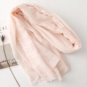 Detail shot of light pink floral embroidery on a soft semi-transparent cotton linen scarf
