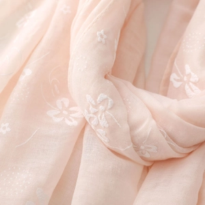 Close-up of pink linen-cotton fabric showing intricate white floral and star embroidery