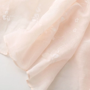 Detailed texture of lightweight pink linen scarf with white floral lily prints