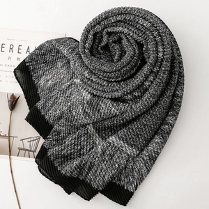 Knitted winter scarf with snowflake texture and black pleated edges on white background