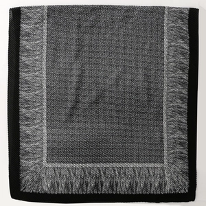 Detailed view of woven texture and fringe tassels on a gray and black scarf