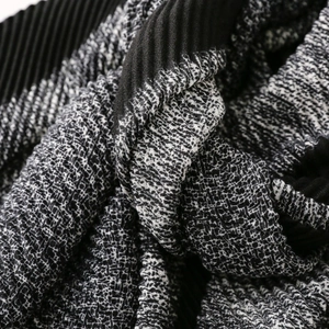 Close-up of contrast textured knit and plissé pleated fabric details on long warm scarf
