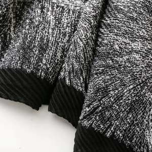 Detail of black and white houndstooth textured fabric with pleated black trim edge