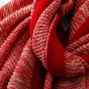 Macro detail of red and white pleated scarf fabric showing soft knitted texture