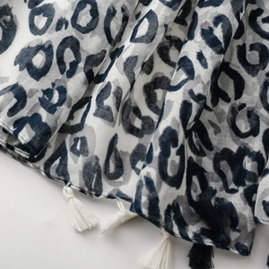 Detail eines blau-weißen Schals mit Leopardenmuster und feinen Baumwollquasten