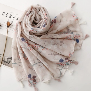Detail of floral linen scarf with berry patterns and tassels next to a magazine