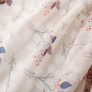 Detailed close-up of breathable cotton fabric with branch and berry floral print patterns