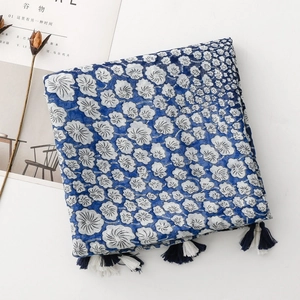 Detail of blue and white floral scarf with tassel fringe on a minimalist background