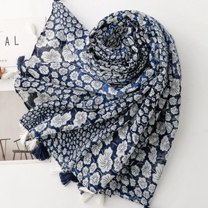 Blue and white floral print cotton scarf with tassel edges on minimalist background