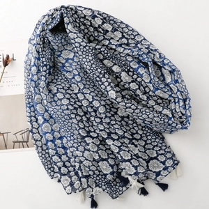Blue and white floral scarf with fringe trim laid flat on a white background