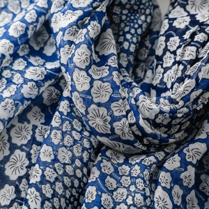 Macro shot of blue and white floral scarf showing soft silk fabric texture and drape