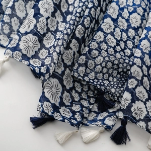 Detail of blue and white floral cotton scarf featuring decorative tassel fringe borders
