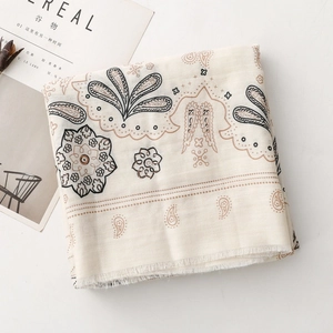 Dettagli di motivi paisley e frange delicate su una sciarpa in cotone beige