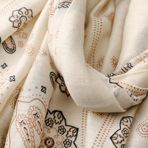 Dettaglio macro del tessuto in cotone satinato crema con motivi floreali paisley vintage