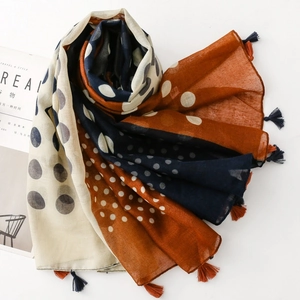 Close-up of polka dot scarf with tassel fringe in caramel and navy contrast tones