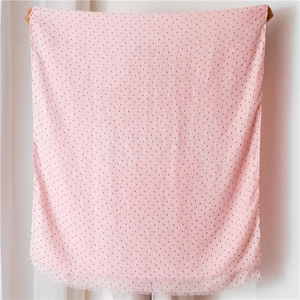 Détail d'une écharpe en coton et lin rose avec motifs de cœurs et bords à franges