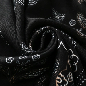 Macro di una sciarpa di raso nero con motivo paisley che mostra la fine trama tessile