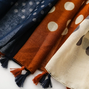 Close-up of retro polka dot scarves in navy, caramel and beige with handmade tassels