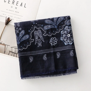 Dettaglio di sciarpa in cotone blu navy con motivo paisley e frange su sfondo bianco