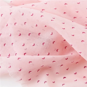 Gros plan sur tissu en coton et lin rose clair avec cœurs et bords effilochés