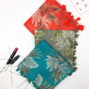Detailed view of tropical leaf pattern scarves with elegant fringe tassels in three colors