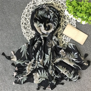 Detail of tropical leaf print and bicolored fringe tassels on black linen shawl