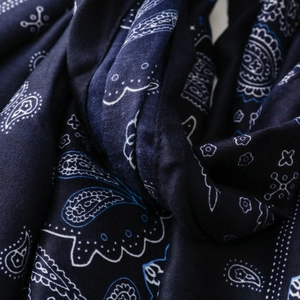 Dettaglio macro di una sciarpa in cotone blu navy con motivi paisley bianchi e azzurri