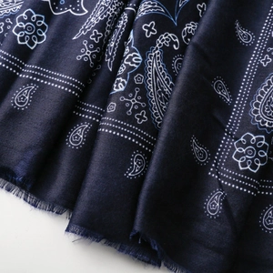 Vista macro di una sciarpa in cotone blu scuro con motivi paisley e bordi con frange fini