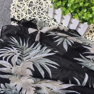 Detail showing tropical palm leaf print and fringe tassels on a linen cotton scarf