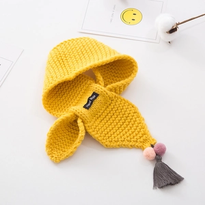 Close-up of handmade yellow knitted hooded scarf with colorful pom-poms and grey tassels