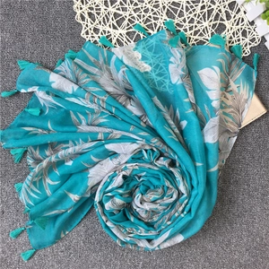 Detail of beach scarf featuring large white leaf prints and dense fringe tassels