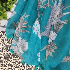 Close-up of tropical banana leaf print on teal linen scarf with fringe tassels