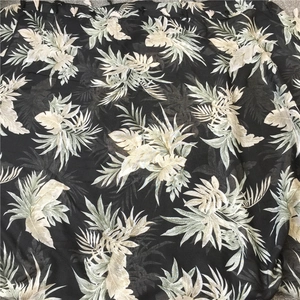 Detail of tropical leaf print on linen beach scarf with fine black fringe tassels