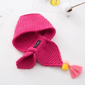 Macro detail of magenta knitted hooded scarf with handmade tag and colorful pompom tassels
