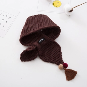 Detail of dark brown knit scarf with plush pom-poms, tassels, and Hand Made label