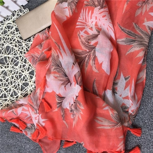 Detail of coral beach shawl showing tropical leaf print and handmade tassels on edges