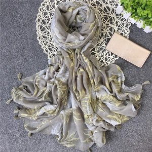 Detail of tropical leaf print scarf with tassels on textured grey background