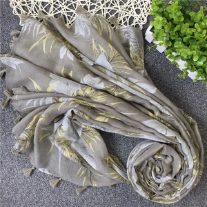 Detail of linen-blend beach scarf featuring tropical leaf prints and fringe tassels