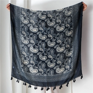 Close-up of ethnic white paisley pattern on soft navy scarf with fringe details