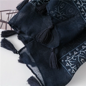 Detail of dark blue ethnic scarf showing paisley patterns and decorative corner tassels