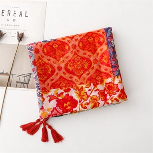 Detailed macro view of colorful ethnic mandala patterns and red tassels on summer shawl