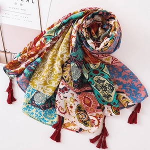Detail of vintage bohemian scarf with colorful floral patterns and red corner tassels