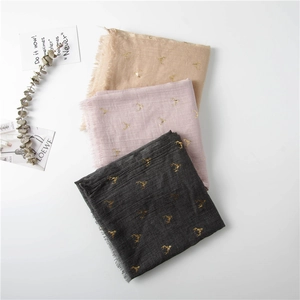 Detail of cotton linen scarves featuring gold foil deer prints and frayed edges in three colors