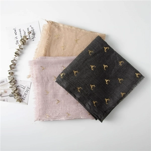 Detailed texture of cotton linen scarves with gold reindeer print and fringed edges